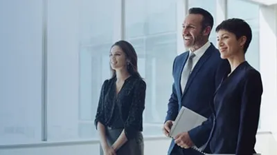Three business professionals standing by an office window