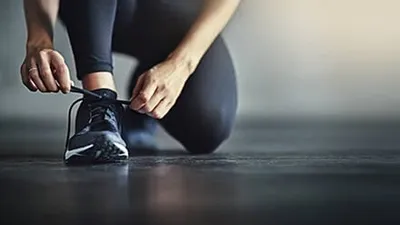 Person kneeling to tie an athletic shoe