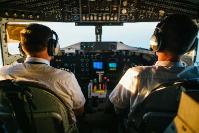 Two pilots in cockpit navigating airplane at high altitude, daylight